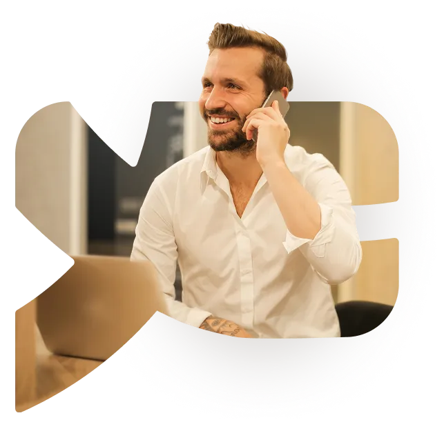 Un utilisateur de YESbusiness au téléphone devant son ordinateur portable, sur une photo découpée à la forme du logo YESbusiness.